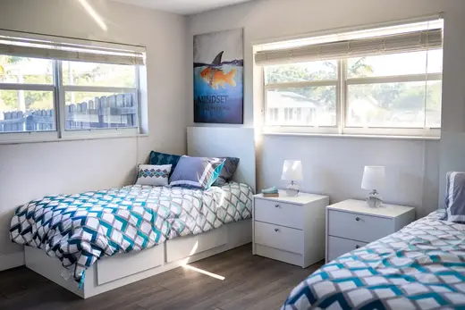 Cozy bedroom with two beds at New You Sober Living, a sober living home in Miami.
